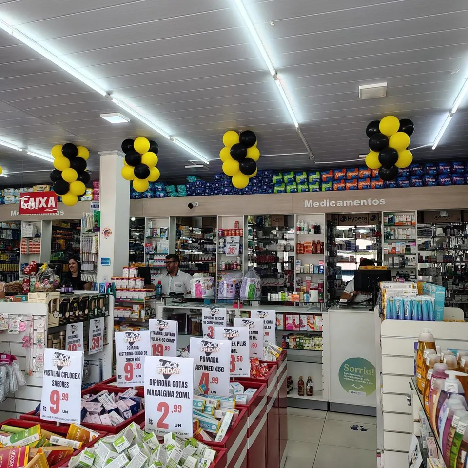 Interior da Leo Farma, com prateleiras de medicamentos e perfumaria e atendentes no balcão